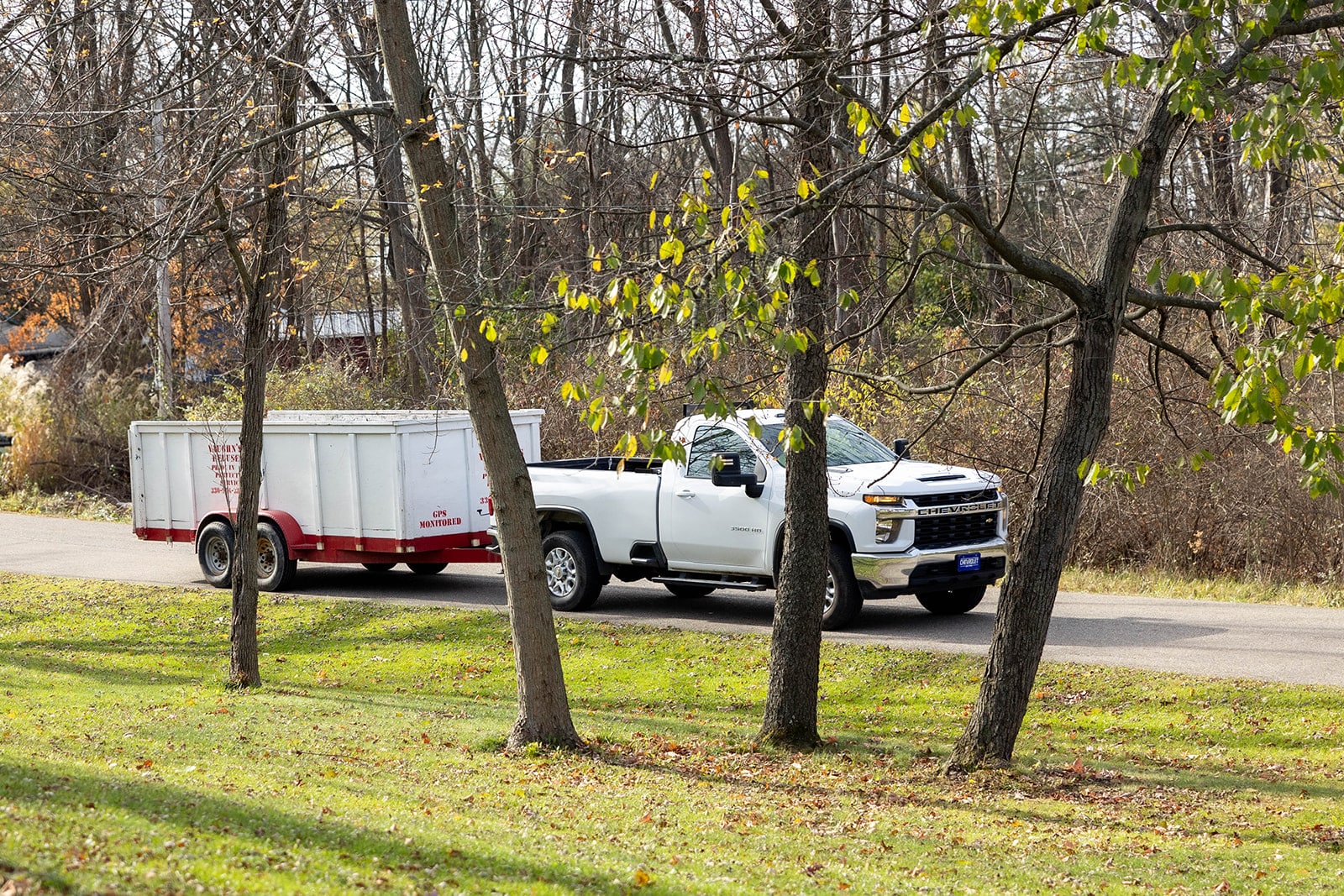 Vaughn's Refuse dumpster being pulled by a truck in a residential area.