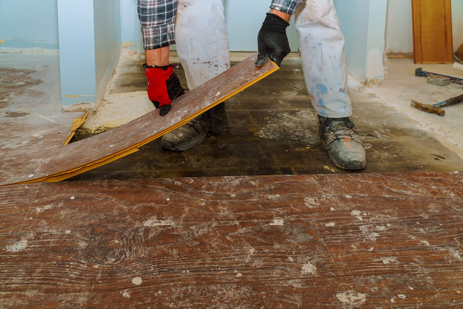 Worker removing damaged wooden flooring during home renovation.