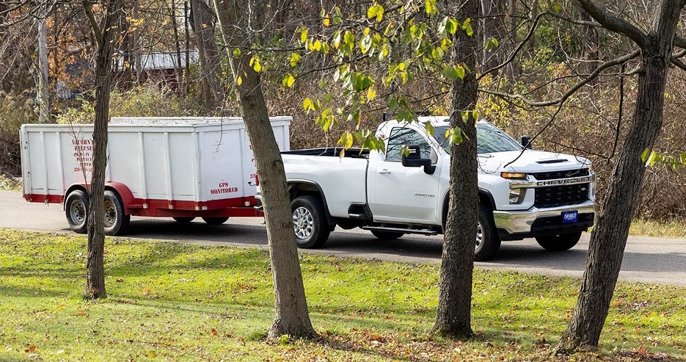 Vaughn's Refuse dumpster being pulled by a truck in a residential area.
